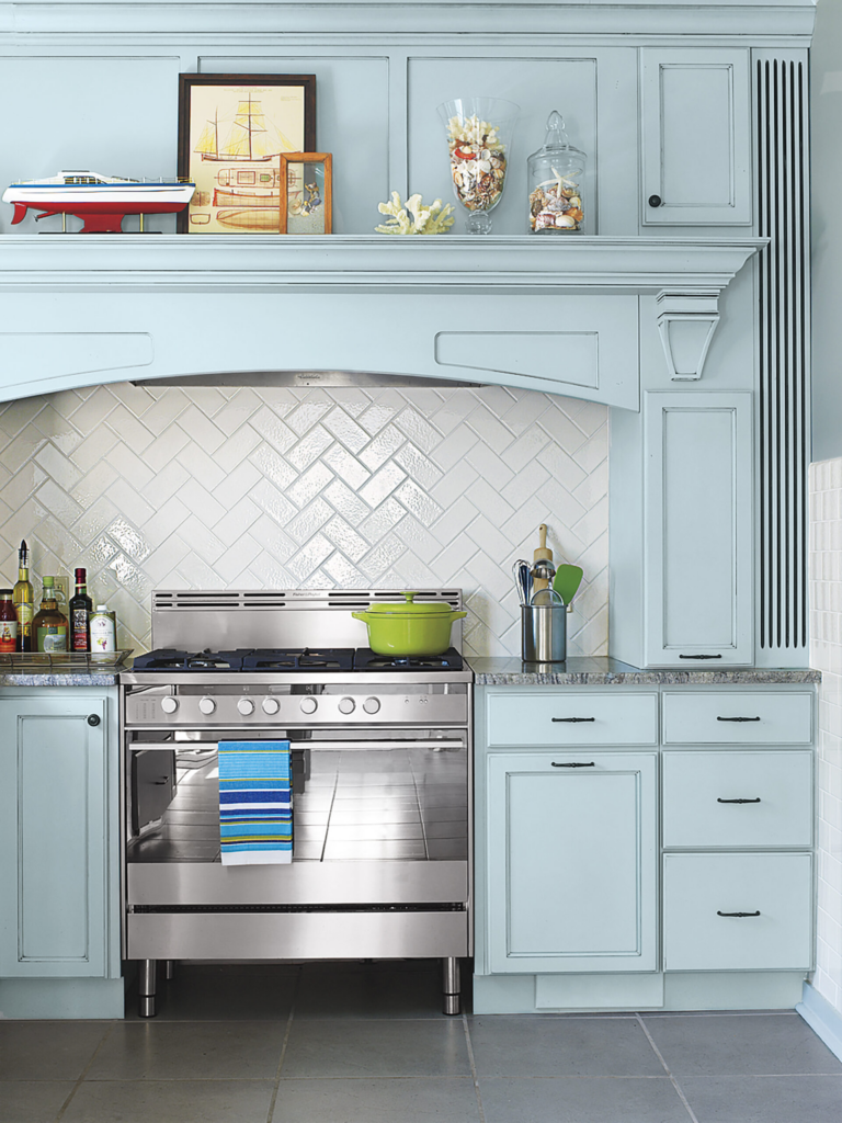 Blue kitchen with white herringbone ceramic subway tile backsplash.