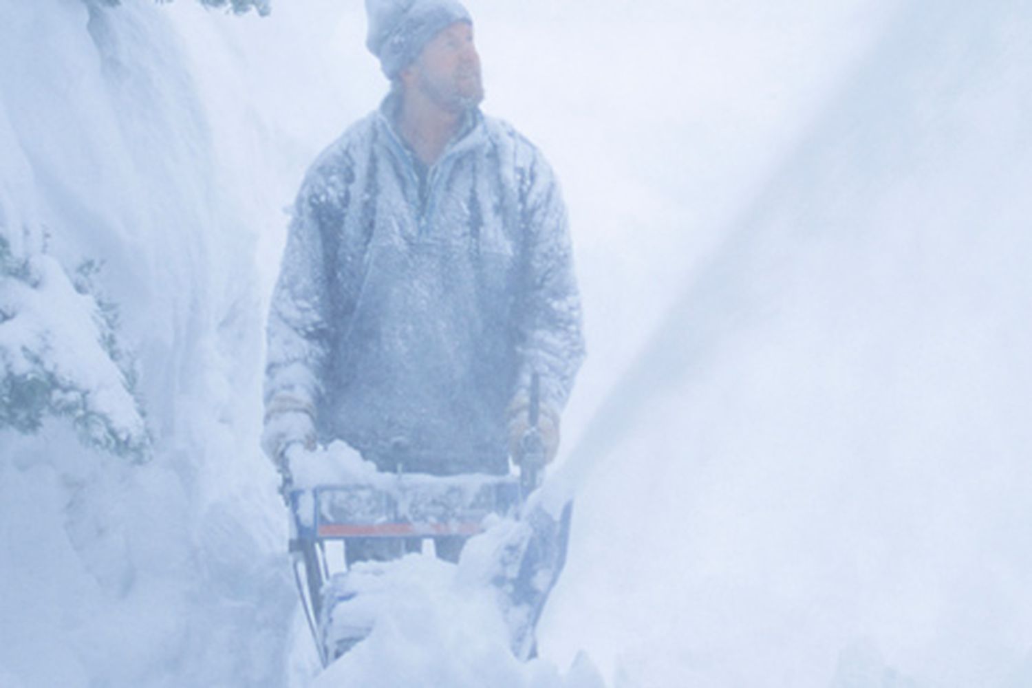 Man using a snowblower to remove snow and ice.
