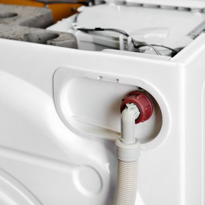 A water inlet hose connected to the back of a residential washing machine.