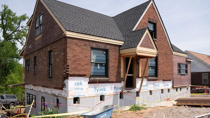 The house is back in place on top of its new foundation and house wrap adds weatherproofing around the border.