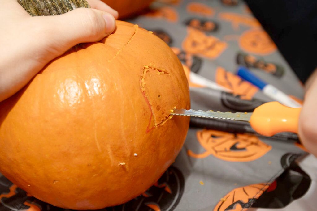 carving the eye of a jack-o-lantern using a serrated blade