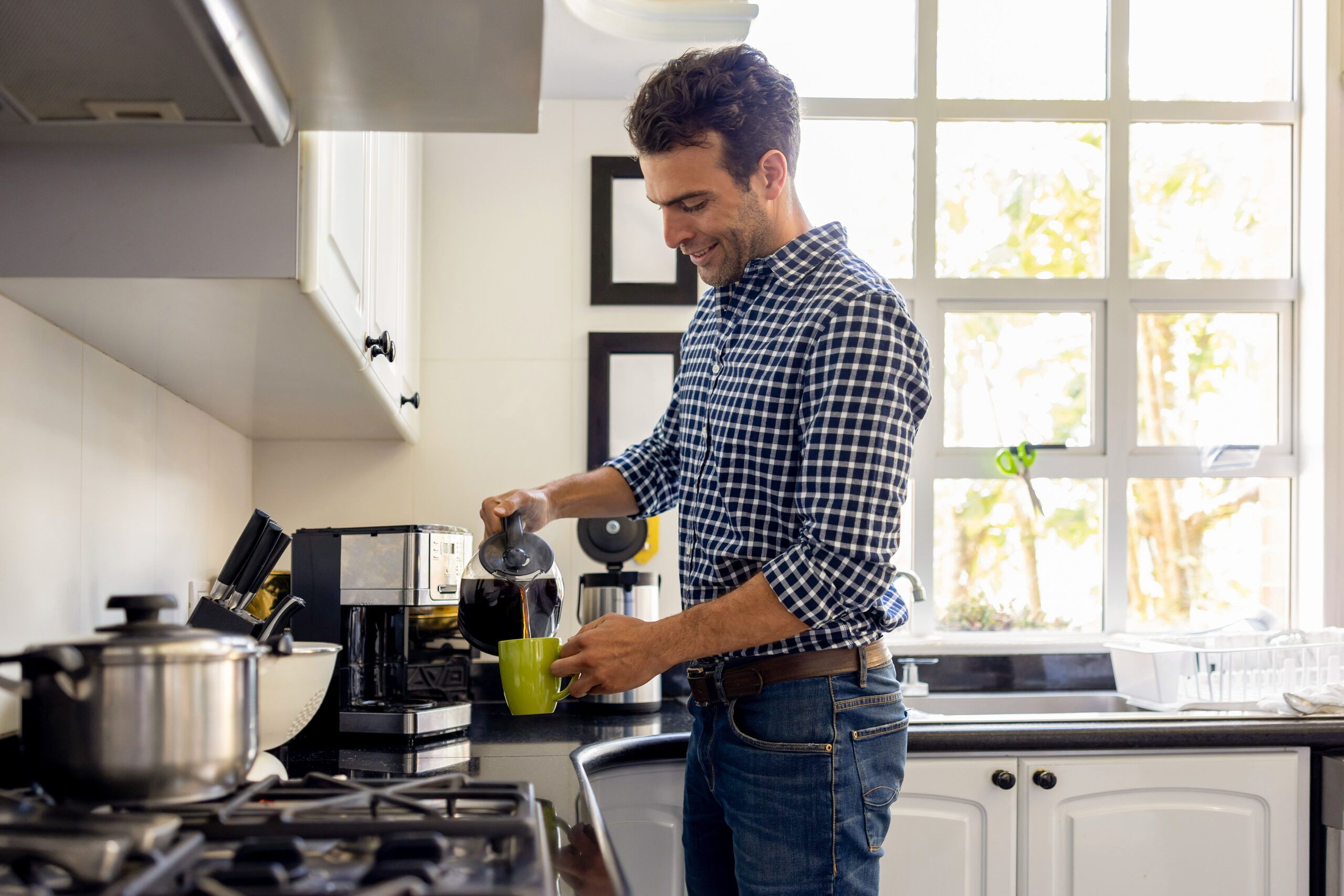 man in a kitchen pouring himself a cup of coffee